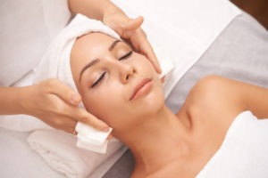 Relaxed woman lying down and receiving a professional facial massage
