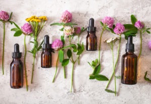 vials of essential oils displayed alongside medical herbs and flowers