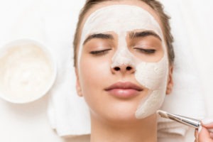 woman relaxing and receiving facial mask and spa therapy