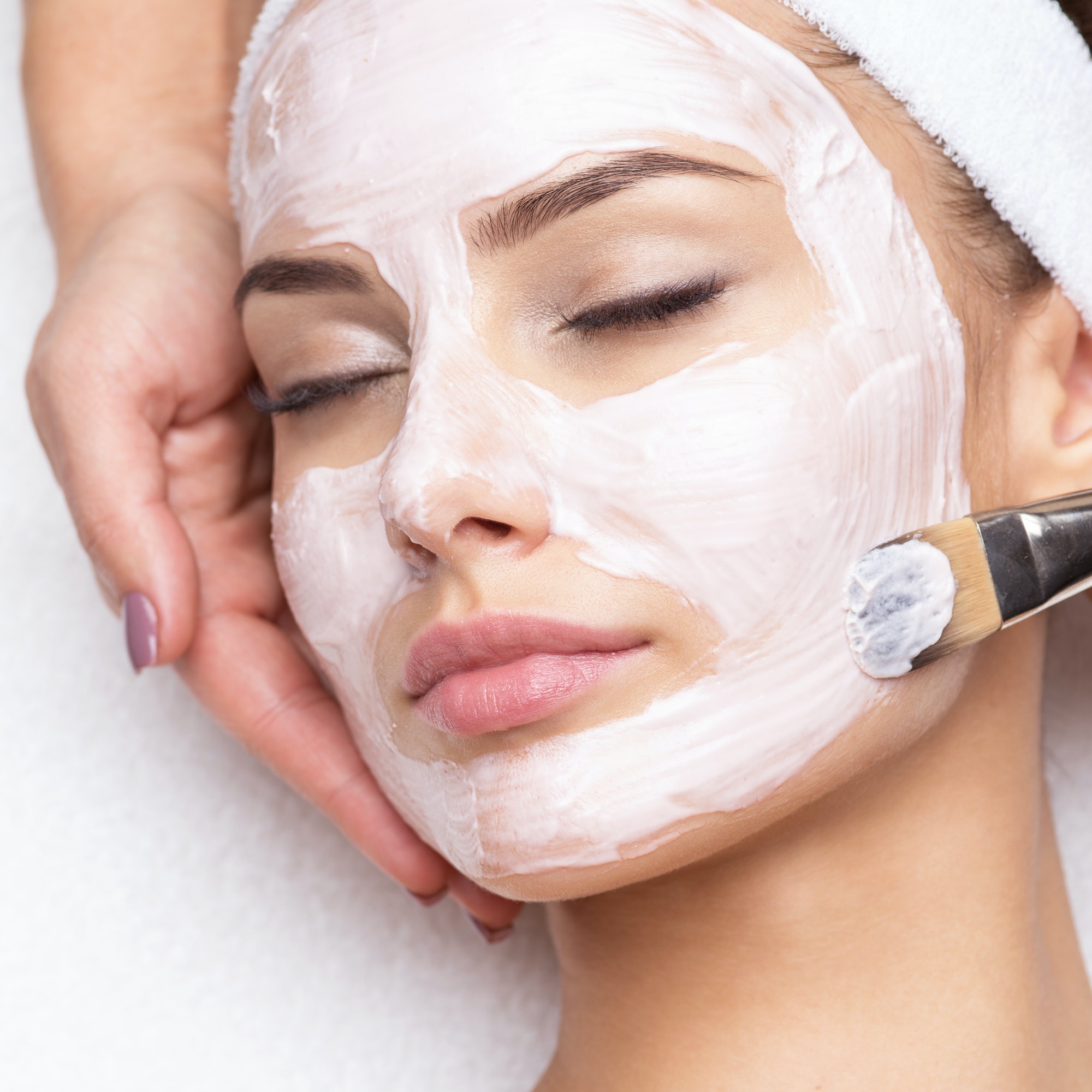 Woman receiving facial mask at beauty salon